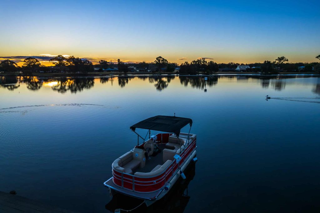 A boat resting on a calm lake under the colorful sunset sky